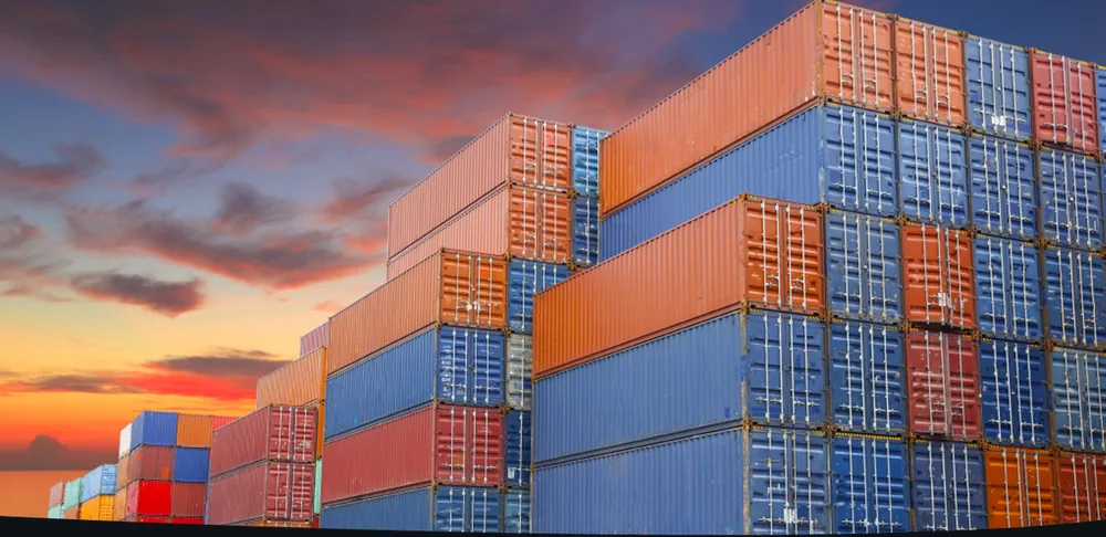 Stacked shipping containers against a sunset sky